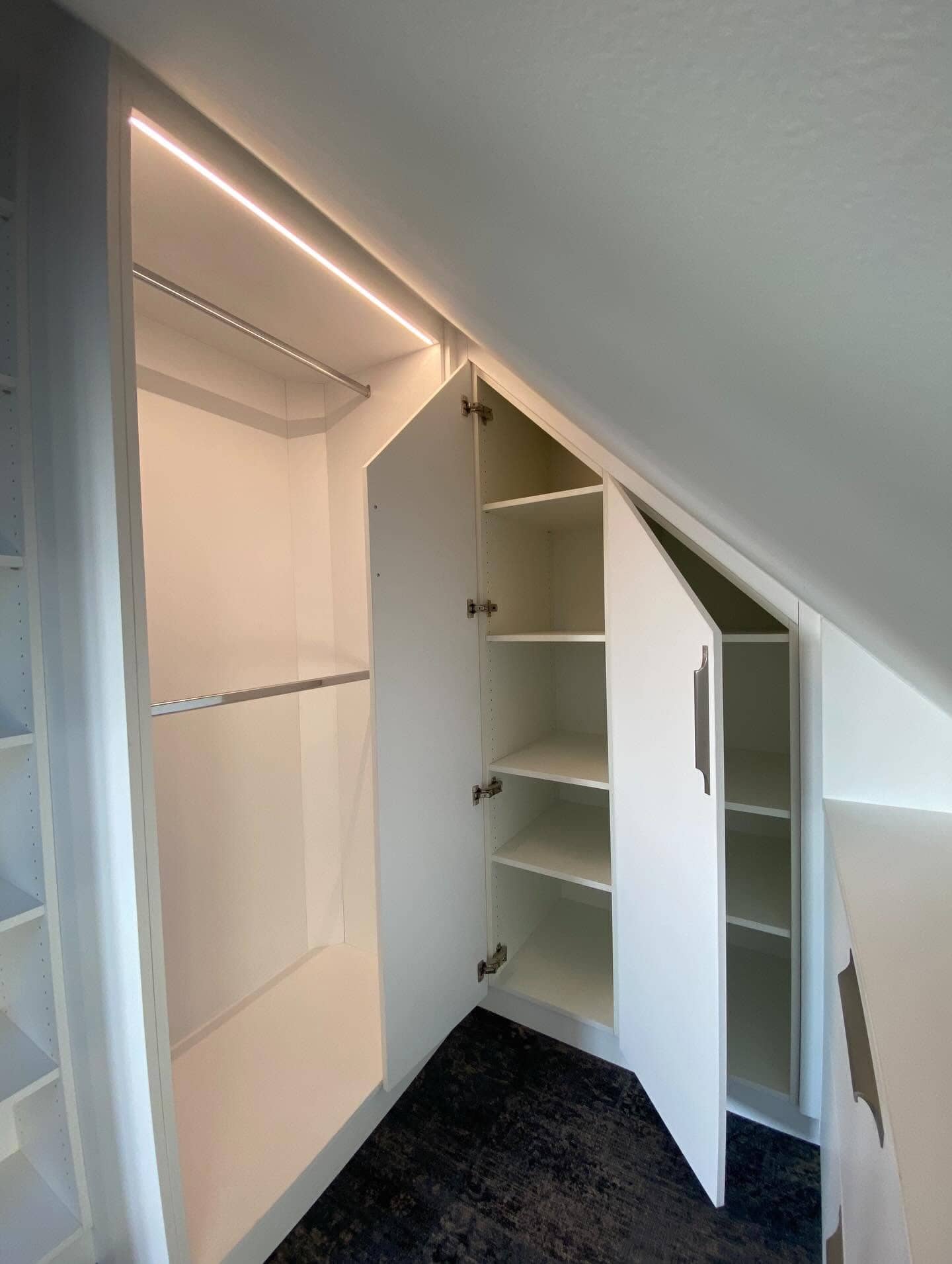 Dressing blanc sous pente aux portes ouvertes, éclairage LED encastré dans les caissons