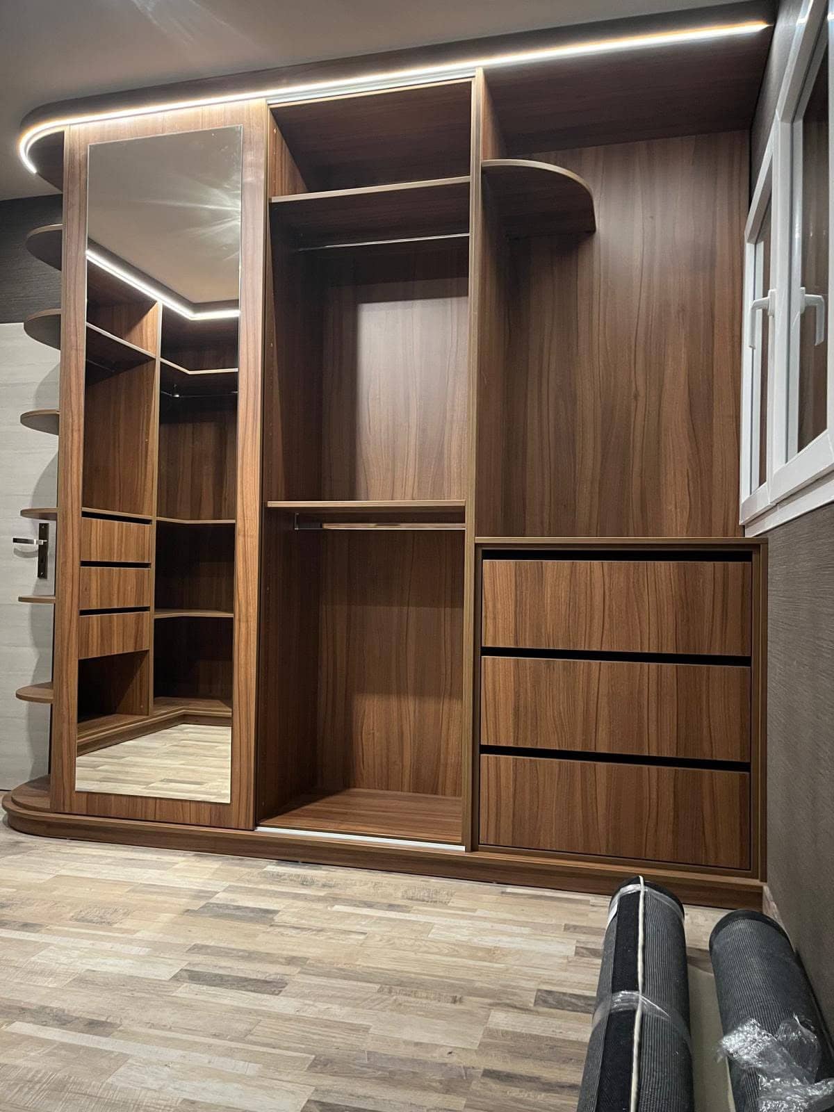 Dressing en noyer avec miroir pleine hauteur, veines de bois appairées d’une porte à l’autre