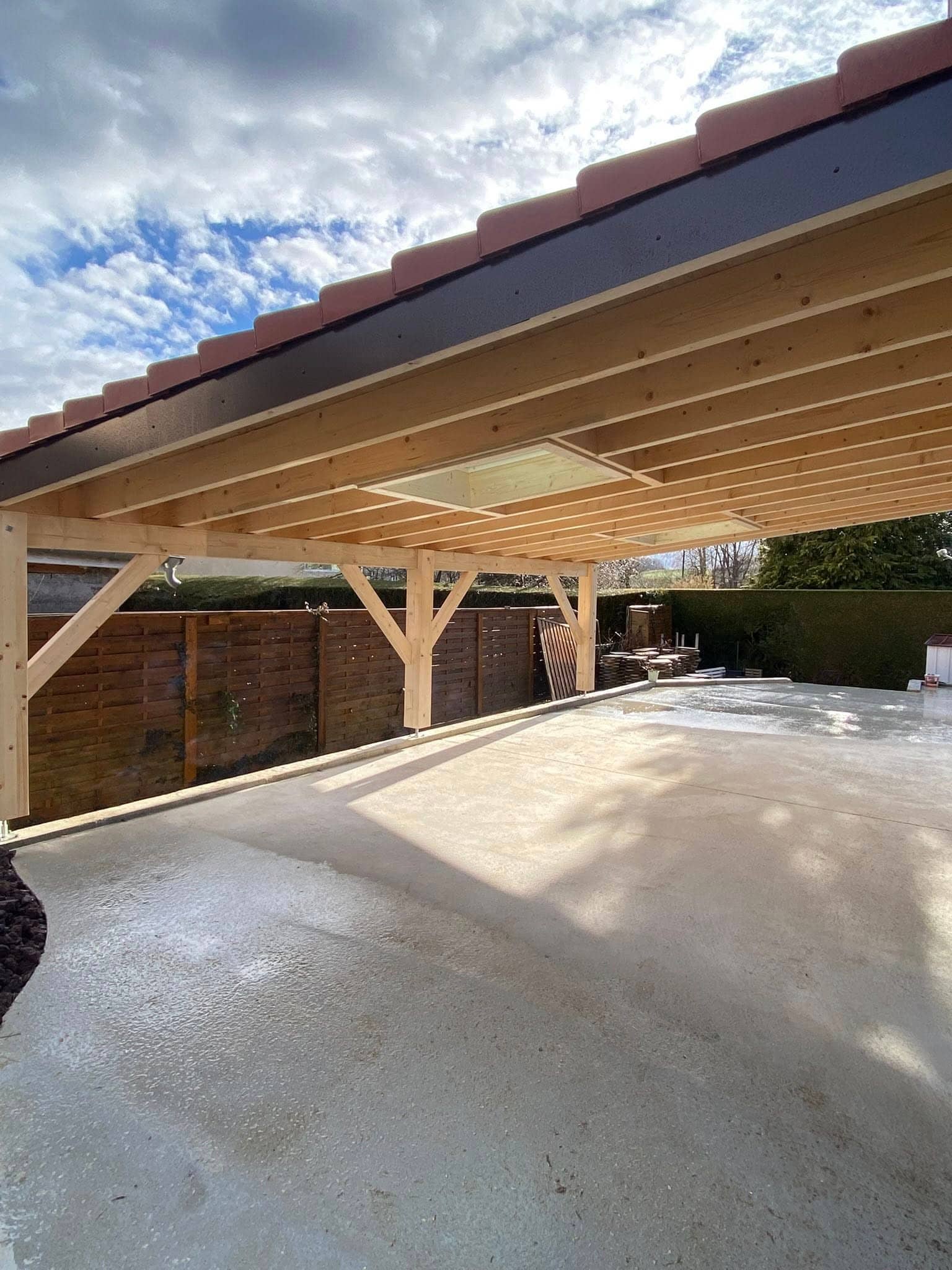 Intérieur d’un carport bois éclairé par des fenêtres de toit